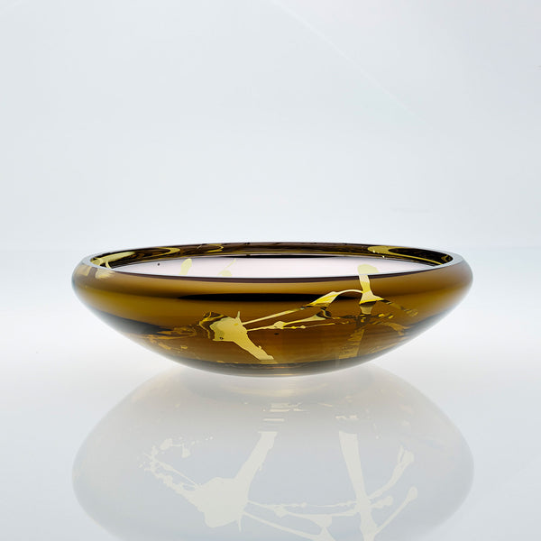 Flat round amber glass bowl with metal interior coating and splashes. Designer glass fruit bowl with mirror effect.